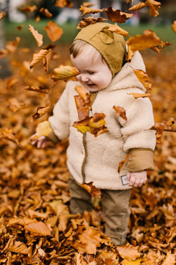 Toddler playing with fall leaves